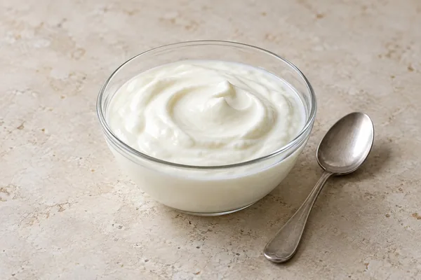 Naturjoghurt in einer Glasschale auf heller Steinfläche